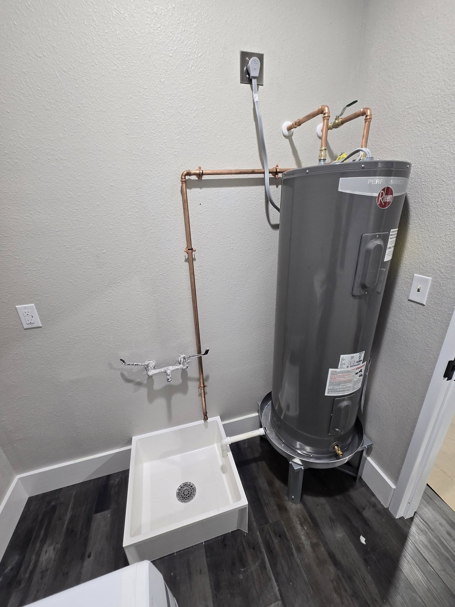 New Rheem Performance water heater installed with copper piping and drain pan by Riley Plumbing.