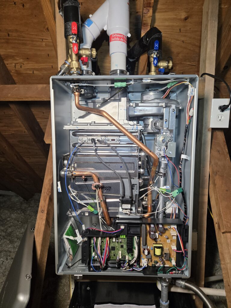 Tankless water heater opened for diagnostic service, showing internal components and valves.