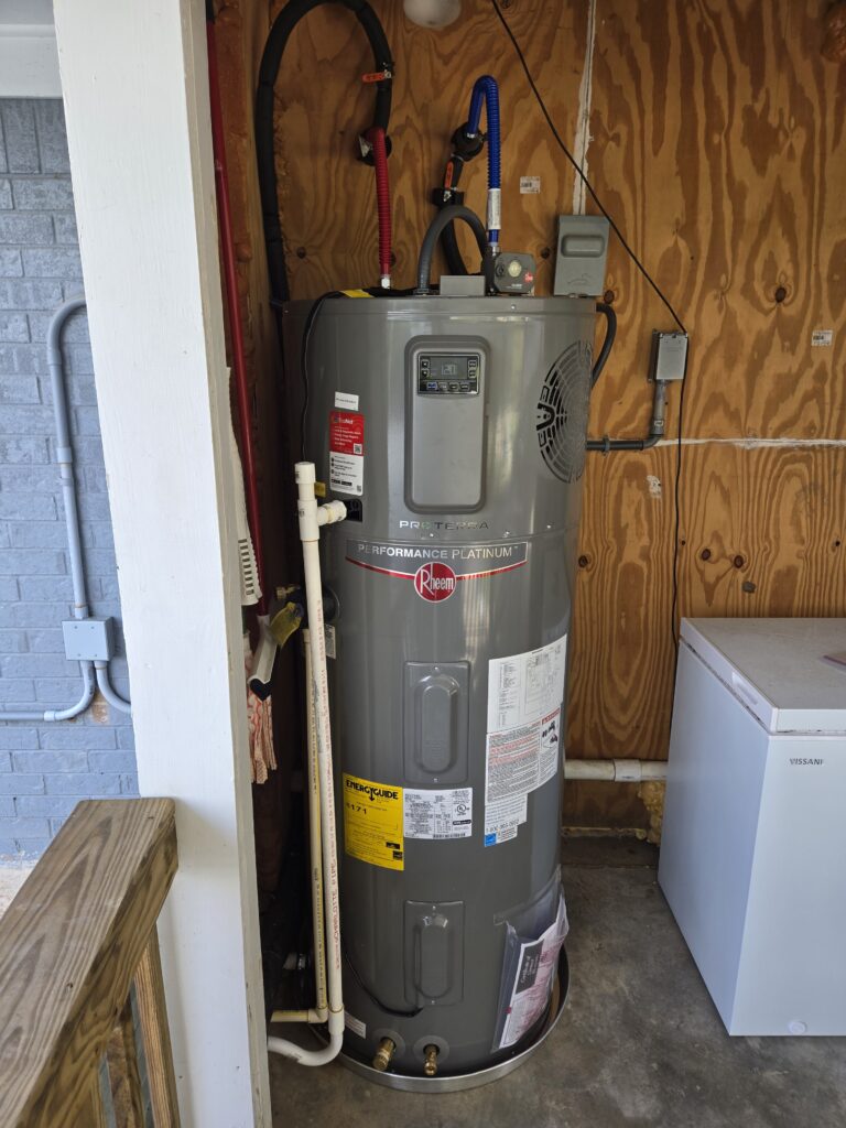 Rheem Performance Platinum water heater installed in a garage utility area with connected plumbing lines.